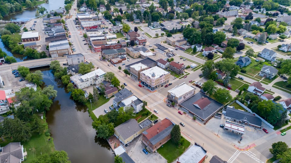 An aerial view of a town with a river, various buildings, and a bridge.