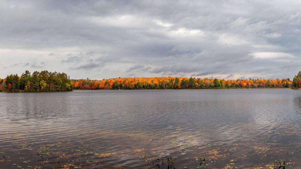 A calm lake surrounded by autumn-colored trees.