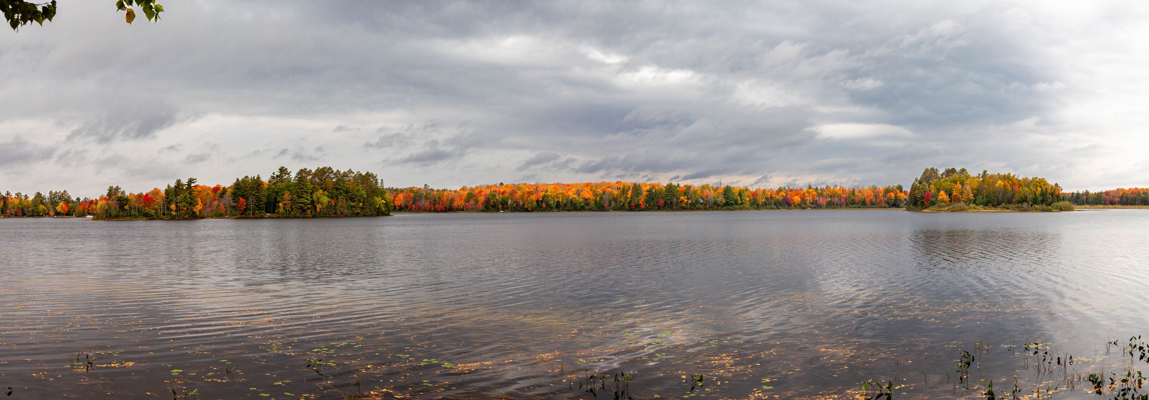 A calm lake surrounded by autumn-colored trees.