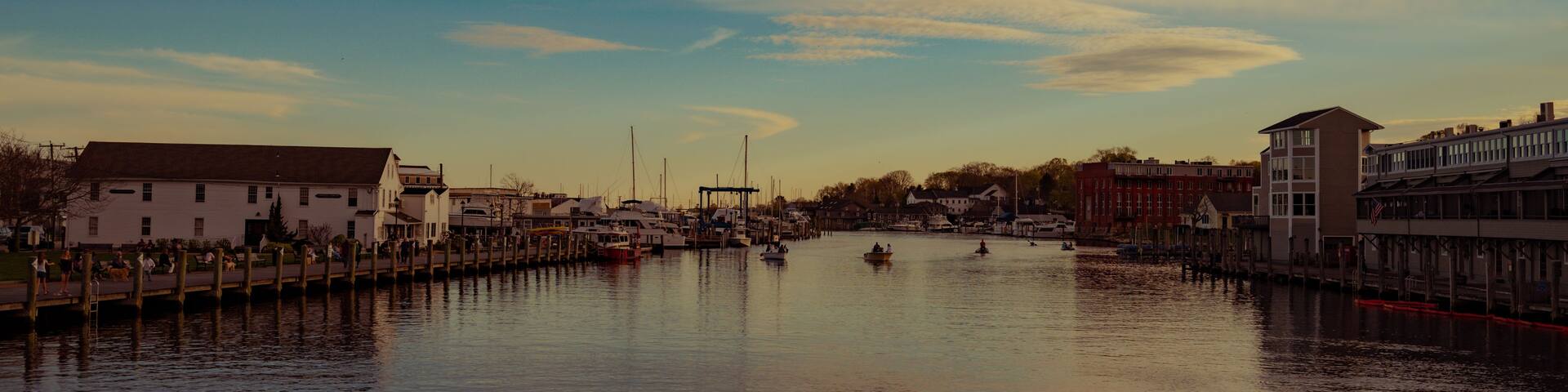 A calm river with boats, waterfront buildings, and a clear sky.