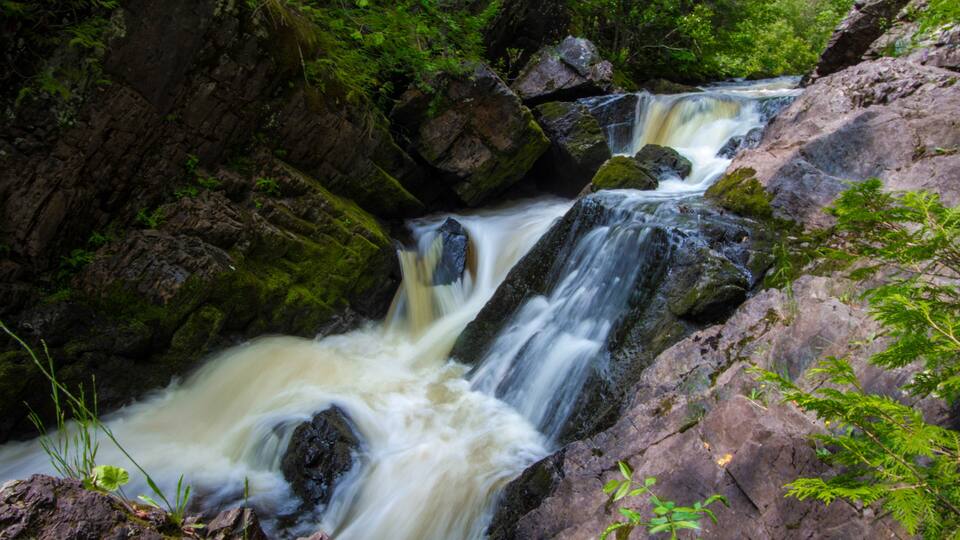 A waterfall cascading over rocks in a forested area.