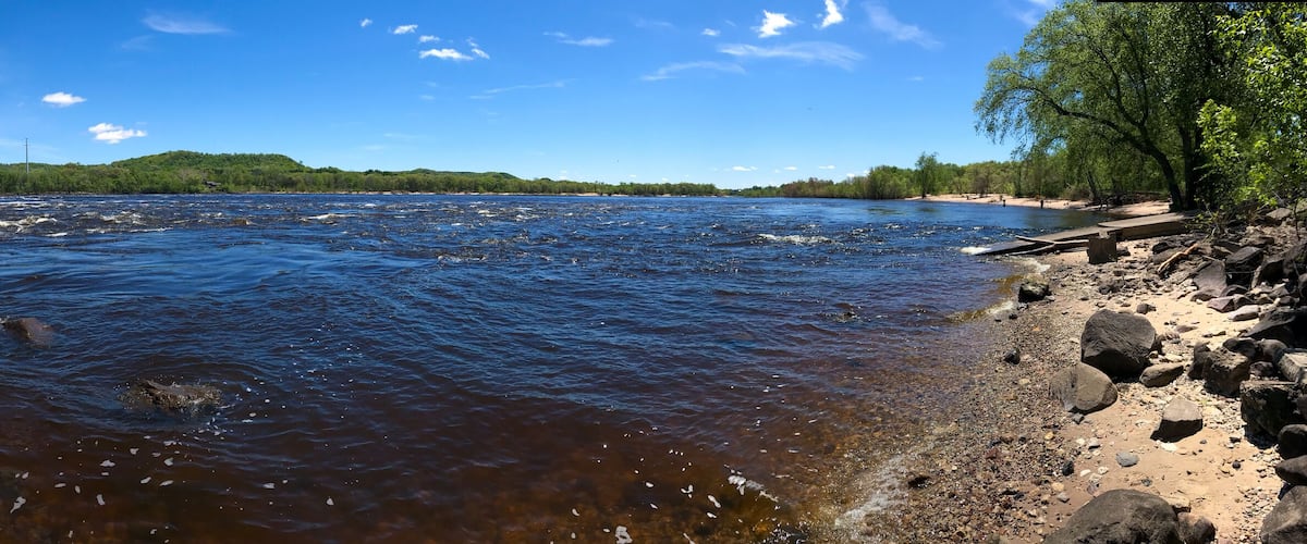 A river with rocks and a building on the left.