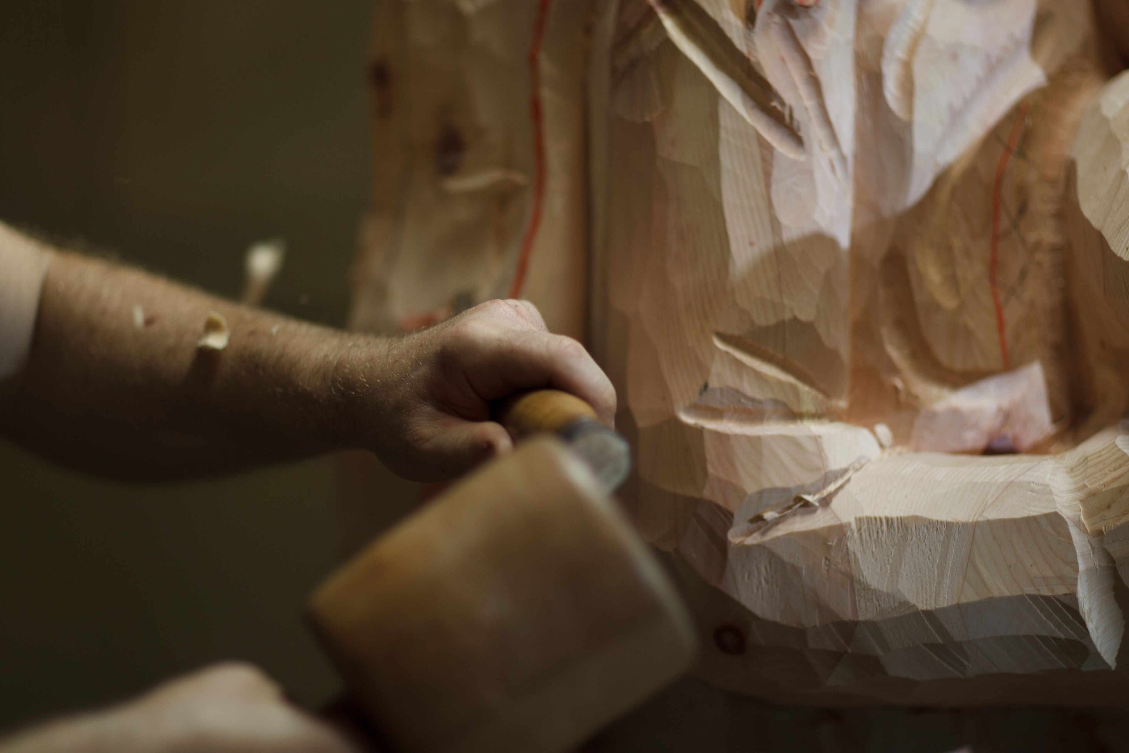 Sculptor using mallet and chisel on wooden statue