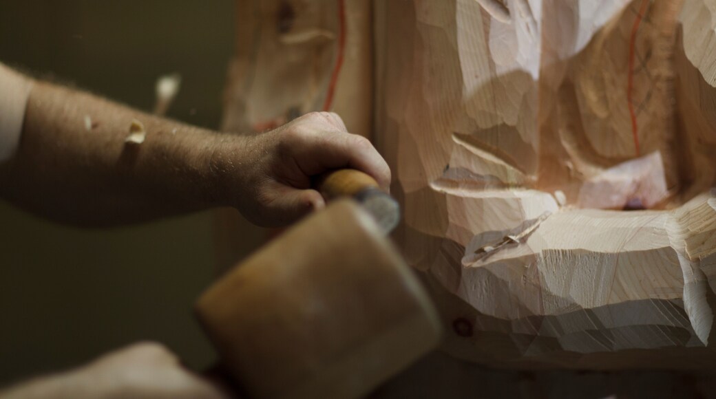 Sculptor using mallet and chisel on wooden statue