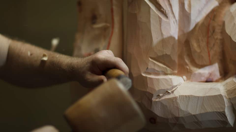 A hand carving a wooden sculpture.