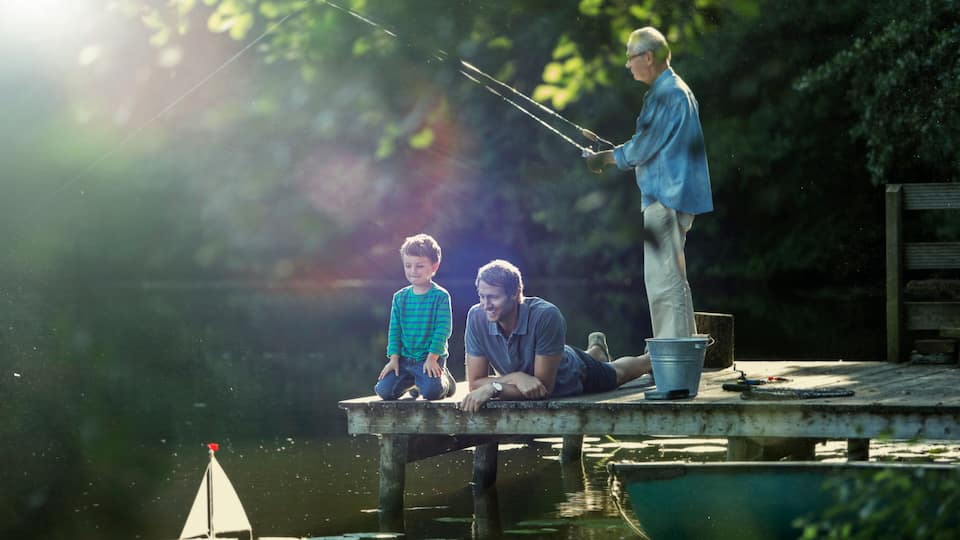 A wooden dock extending into a body of water with a sailboat and a fishing rod.
