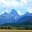 Une chaîne de montagnes avec un sommet imposant, une vallée bordée de forêts denses et un petit village au premier plan.
