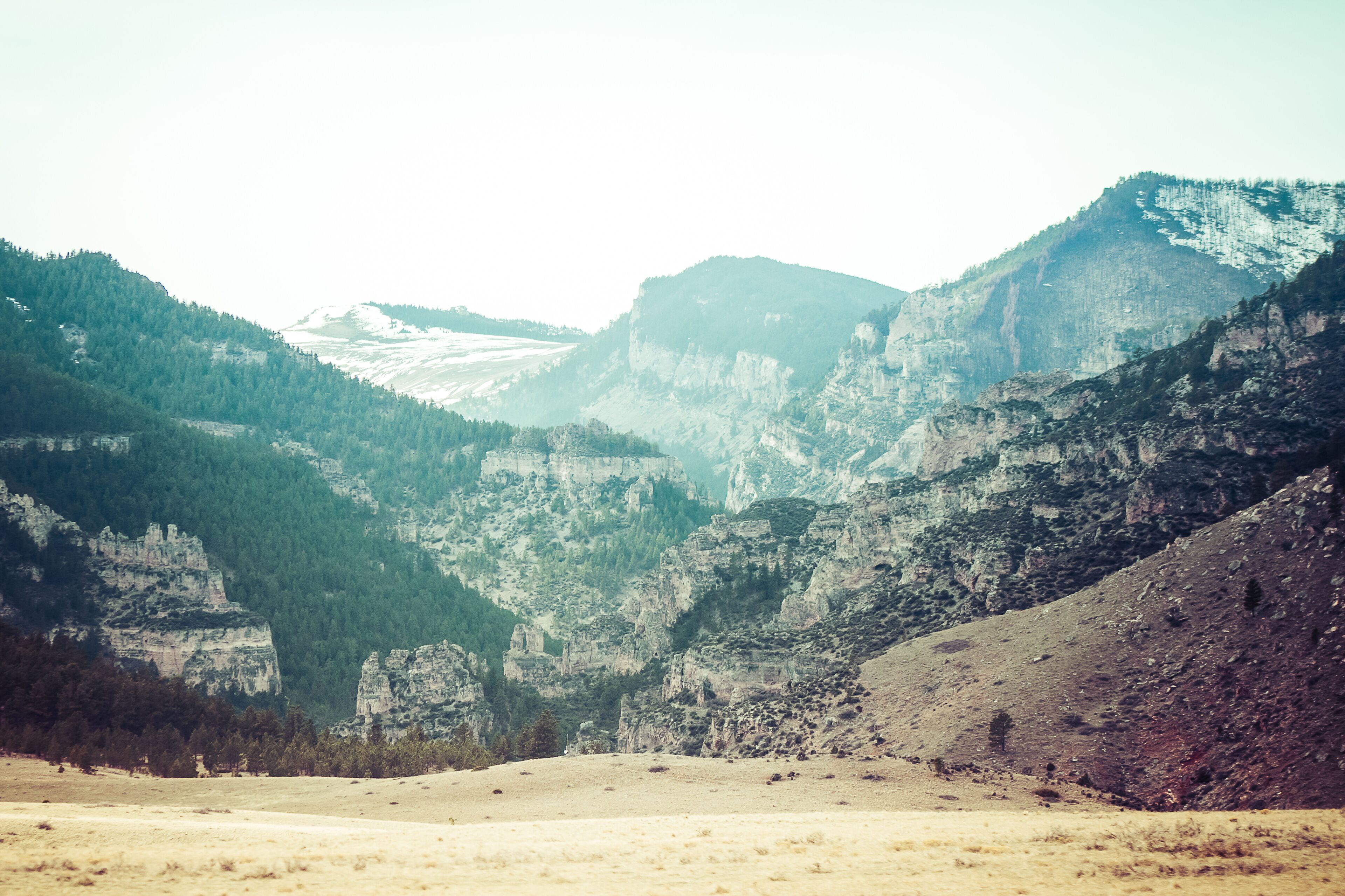 A mountainous landscape with a valley, rocky cliffs, and dense forests.