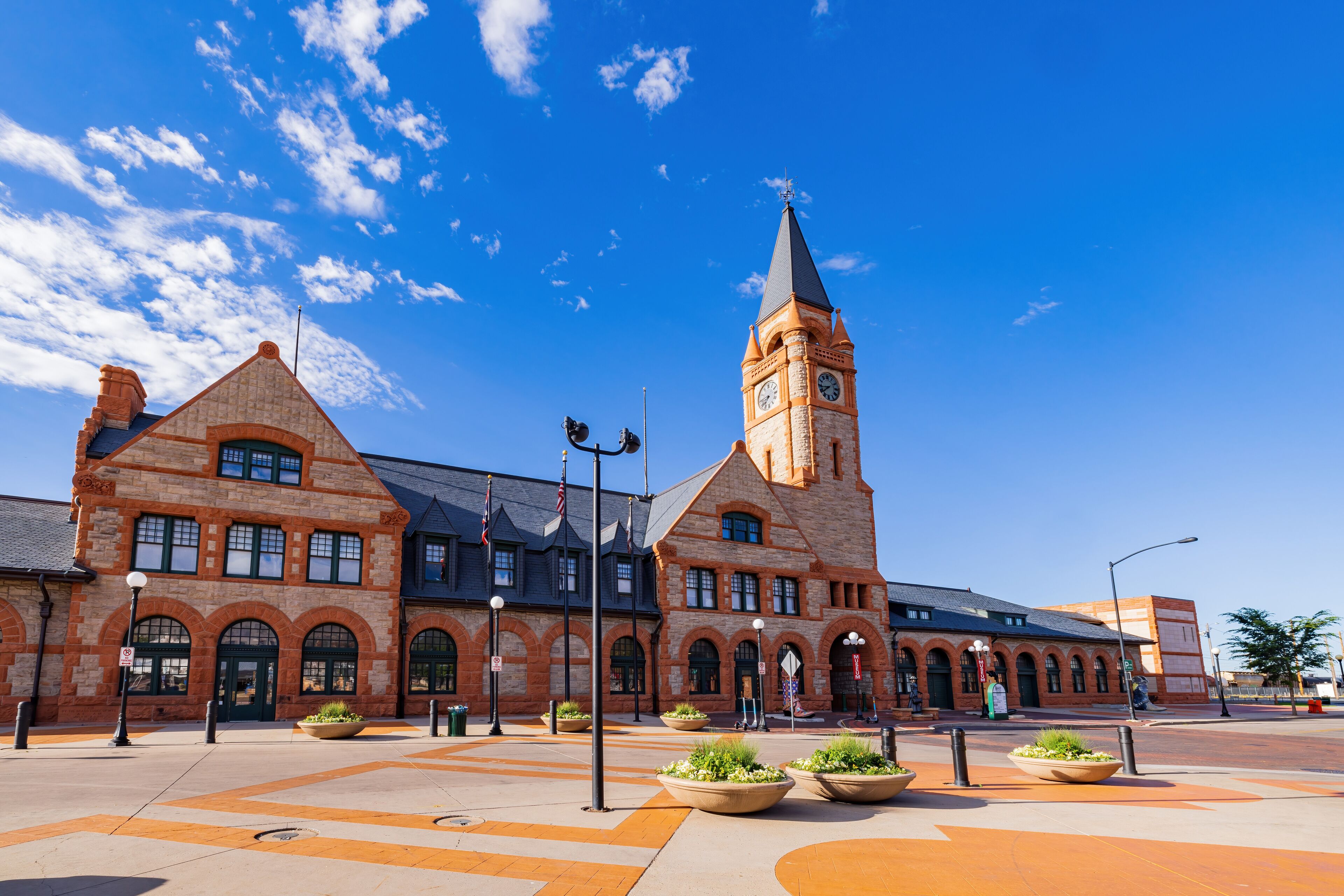 A historic building with a clock tower, arched windows, and a central courtyard with planters.