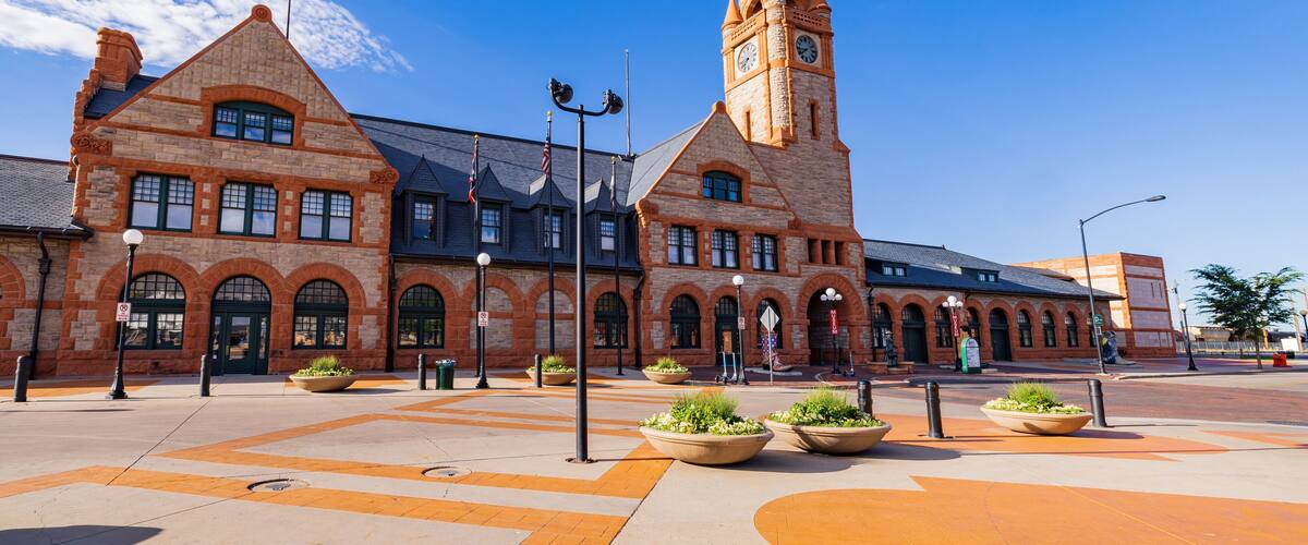 A historic building with a clock tower, arched windows, and a central courtyard with planters.