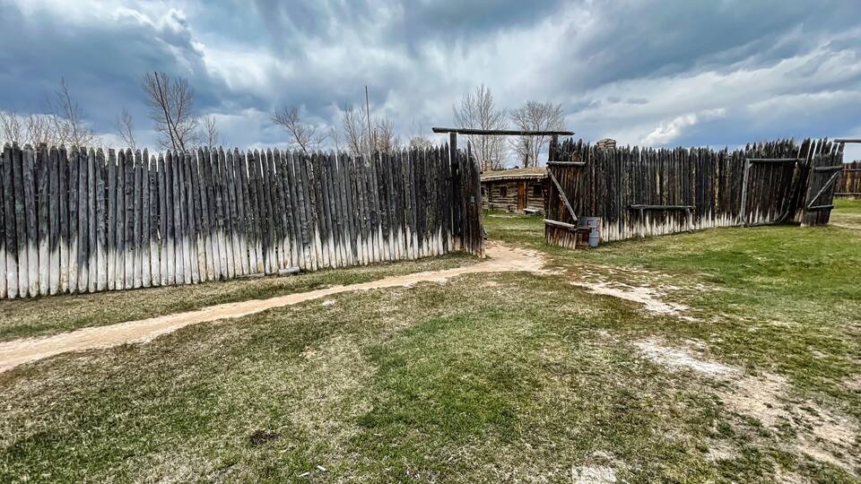 A fenced yard with a dirt path leading to a wooden structure.