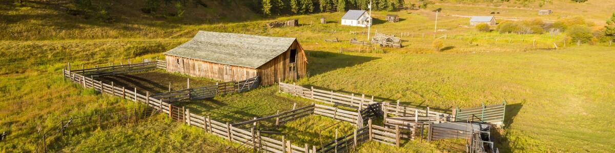 Aerial view of a rustic farm, featuring a wooden barn, and various fences. Ranch land in the fall. , Newcastle, Wyoming, USA.