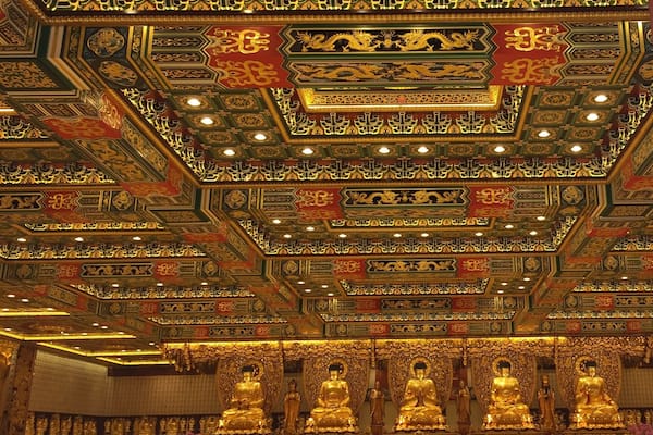 A richly decorated temple interior with ornate golden ceilings and golden statues.