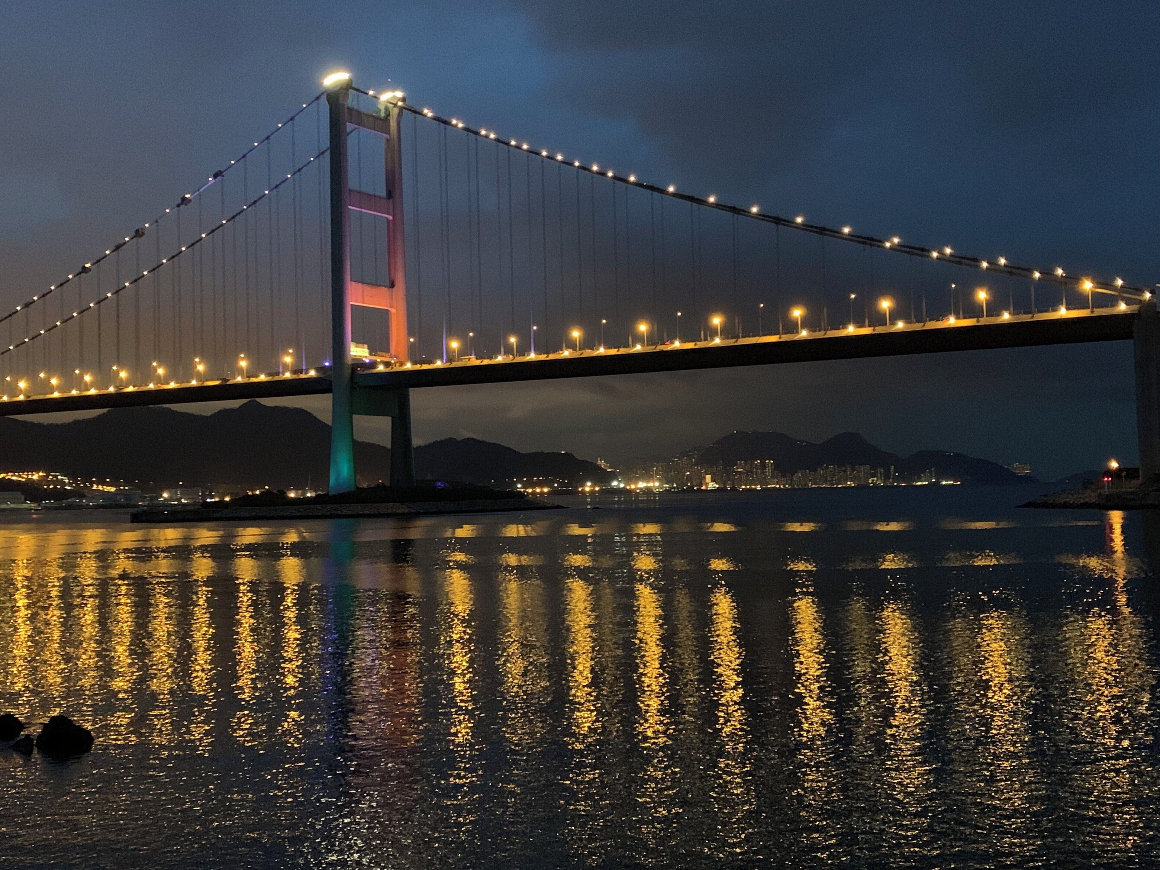 A bridge at night with lights reflecting on the water.
