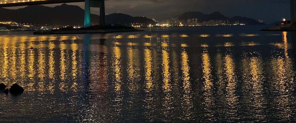 A bridge at night with lights reflecting on the water.