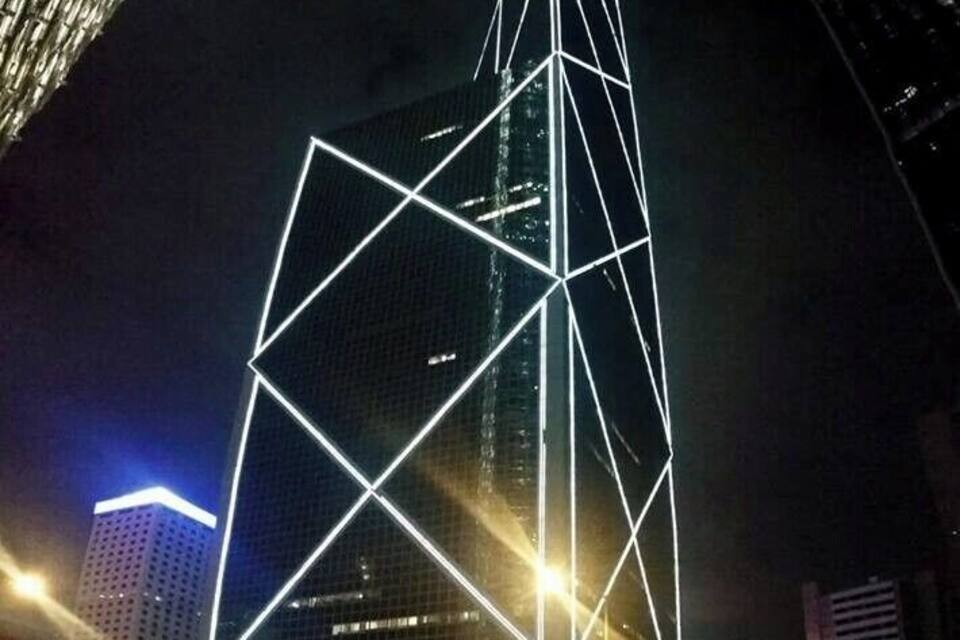 Een modern gebouw met een geometrisch gevelontwerp, verlicht in de nacht.