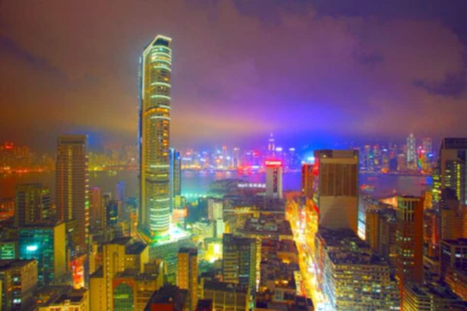 A cityscape at night with illuminated buildings and a prominent skyscraper.