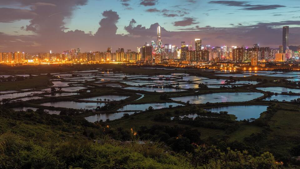 This is a great location for a sunset shoot contrasting fish farms in rural Hong Kong with the built up city of Shenzhen.
To get there you can take the 76K bus from either Yuen Long of Sheung Shui, get off at Ho Sheung Heung then take the green mini bus 51B from around the corner to Ma Tso Lung Shun Yee San Tsuen. From there it's a 150m hike up the old road to the former police post. The best spot is a hill just to the north of the police post.