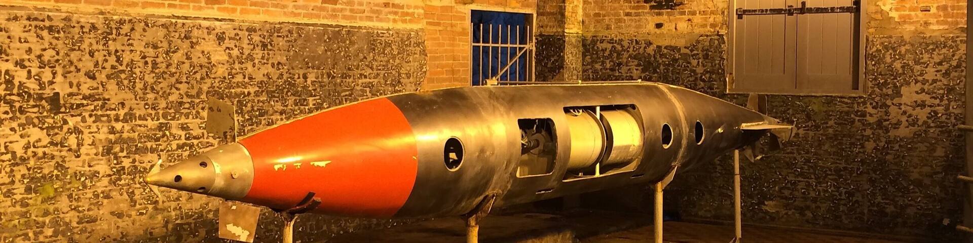 A missile on display in a brick-walled room.