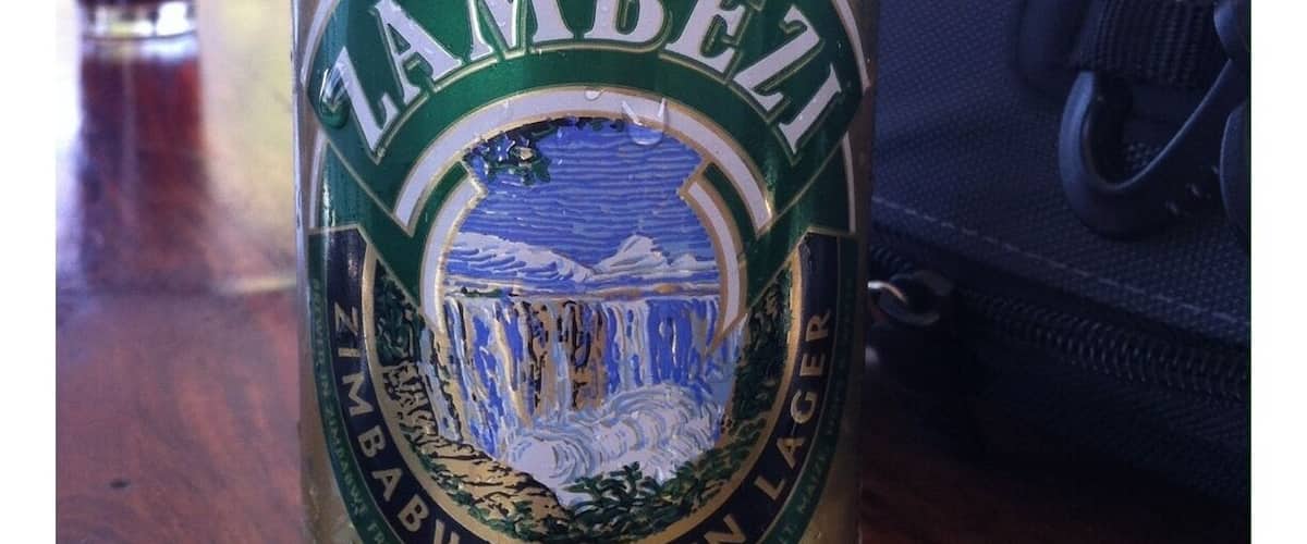 A can of Zambezi beer with a label featuring a waterfall and mountains.