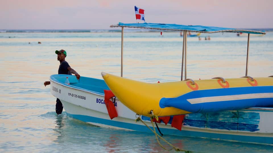 A man in a boat with a flag, a lifebuoy, and a canopy.