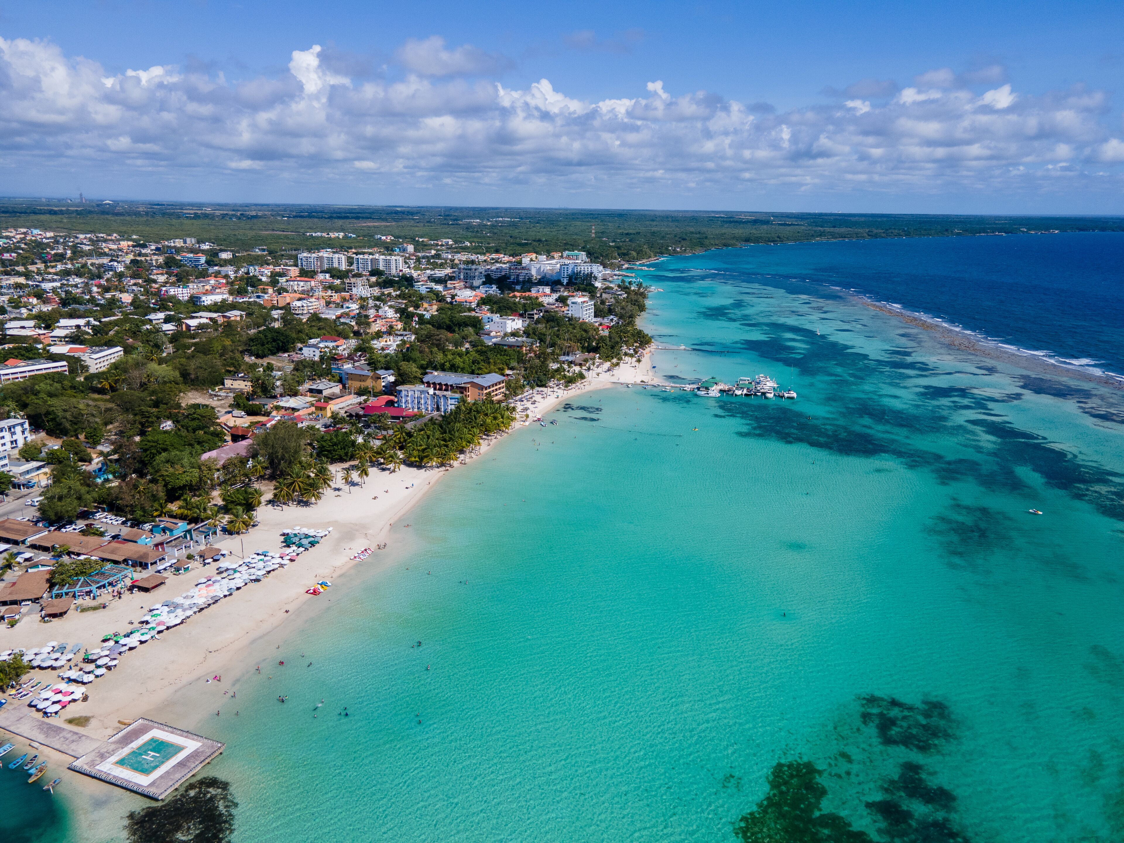 A coastal city with a beach, clear turquoise waters, and a marina.