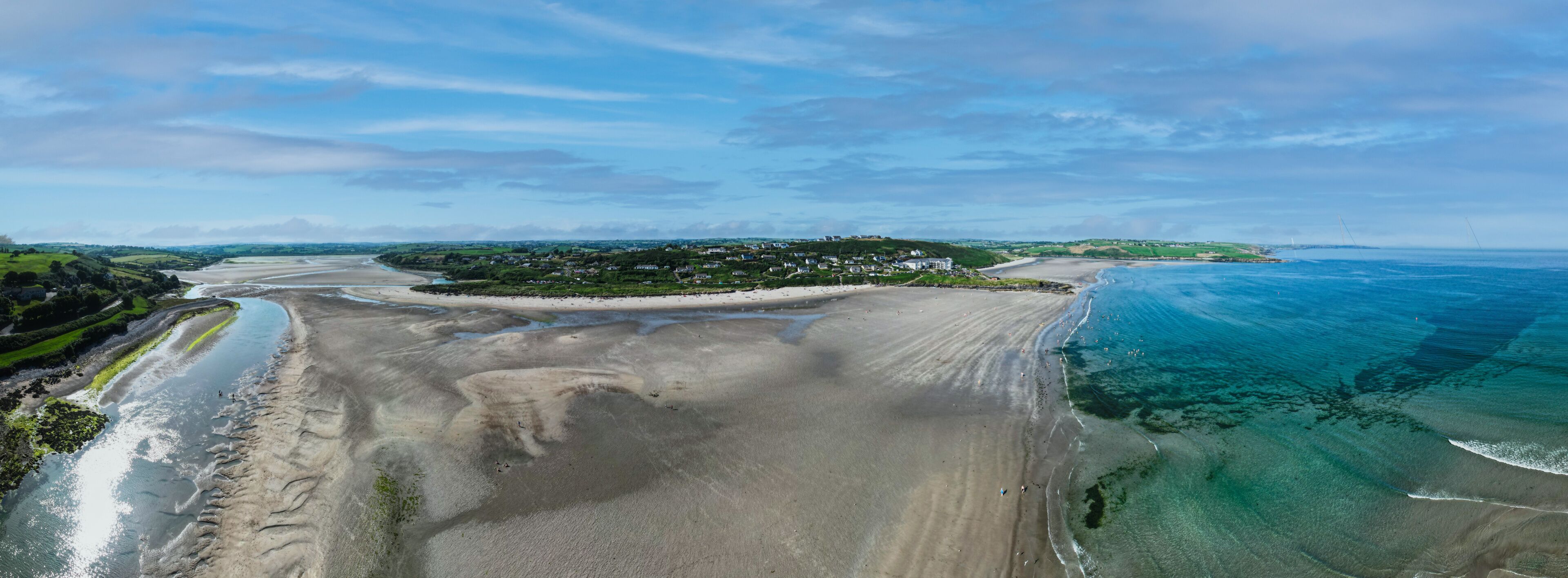Aerial view of Inchydoney beach near Clonakilty in Ireland with people in the turquoise water on a warm summer day