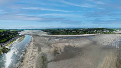 Aerial view of Inchydoney beach near Clonakilty in Ireland with people in the turquoise water on a warm summer day