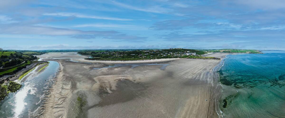 A coastal landscape with a beach, a river, and a distant village.