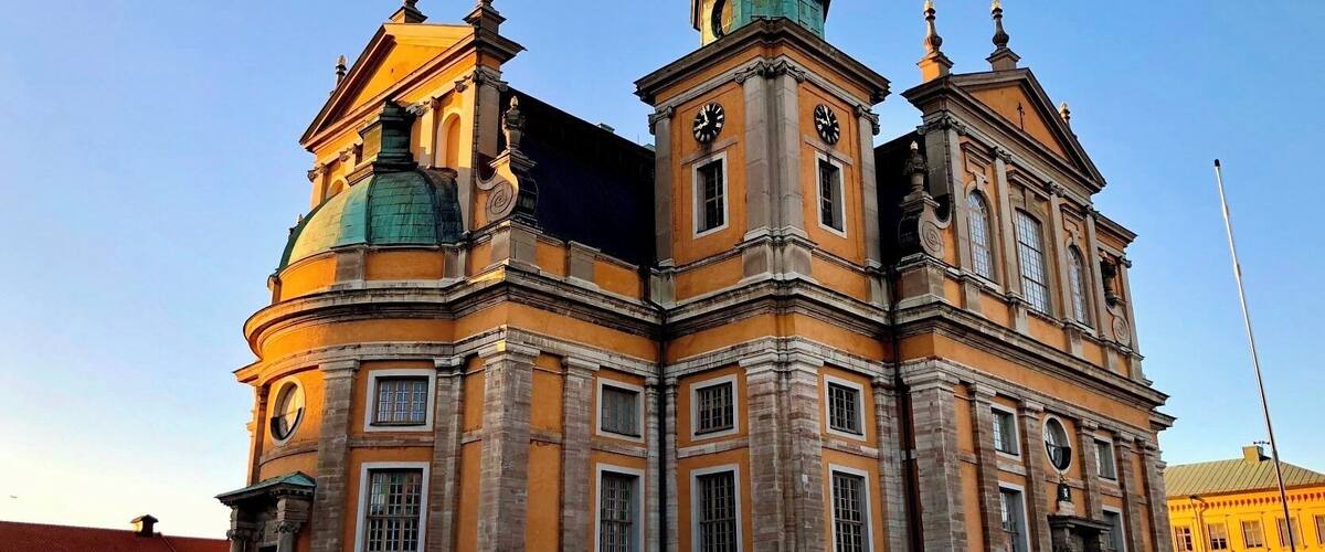 A historic building with a green dome and clock towers.