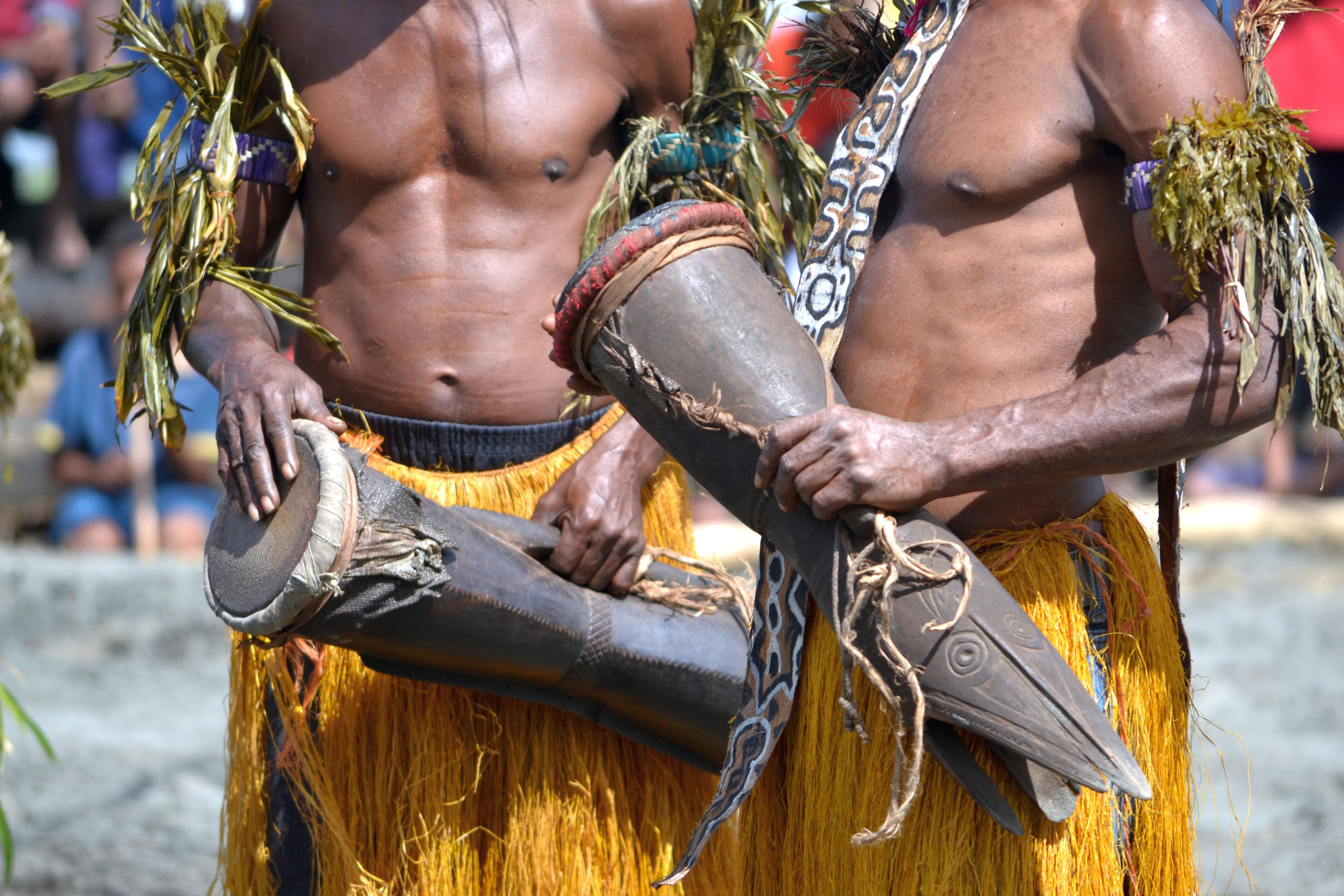 Two individuals in traditional attire holding ceremonial objects.