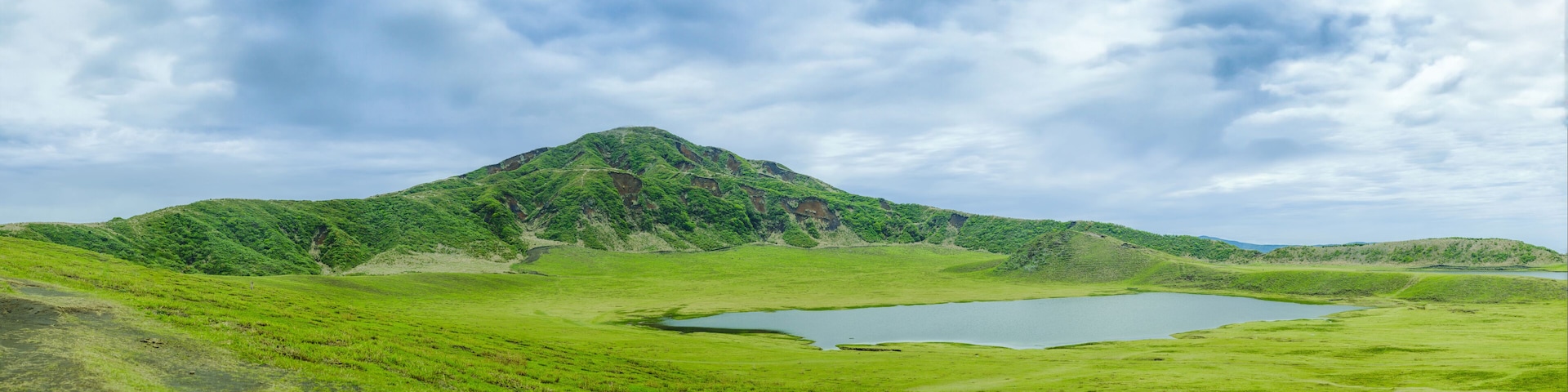 A green valley with a lake and a mountain.