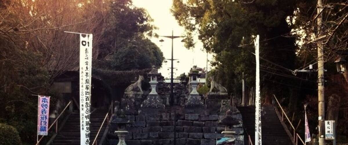 A stone pathway leading to a traditional Japanese shrine with steps and stone lanterns.