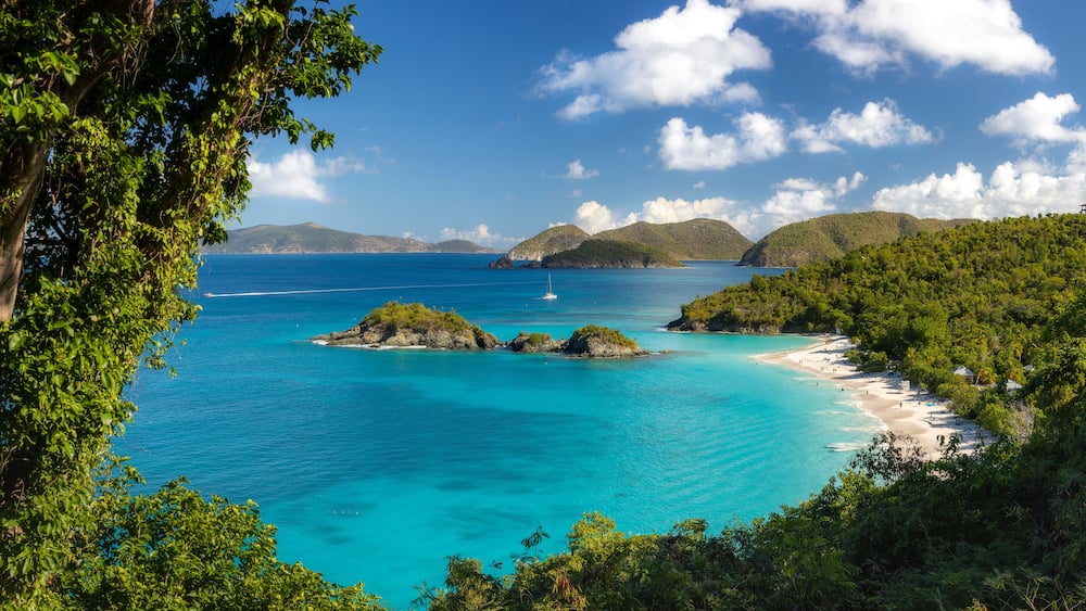 Une mer turquoise, une plage de sable et des collines verdoyantes.