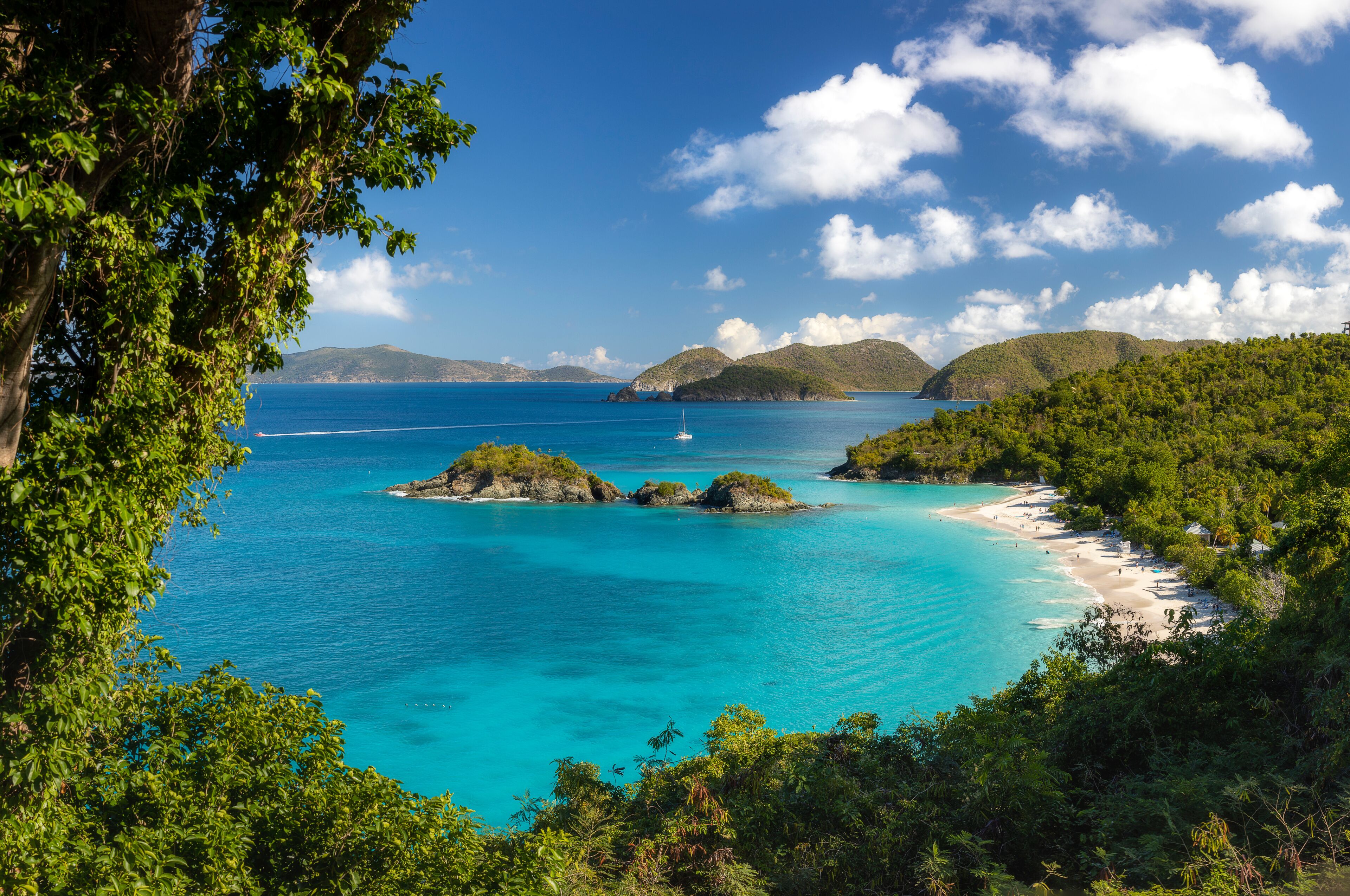 A turquoise sea, a sandy beach, and lush green hills.