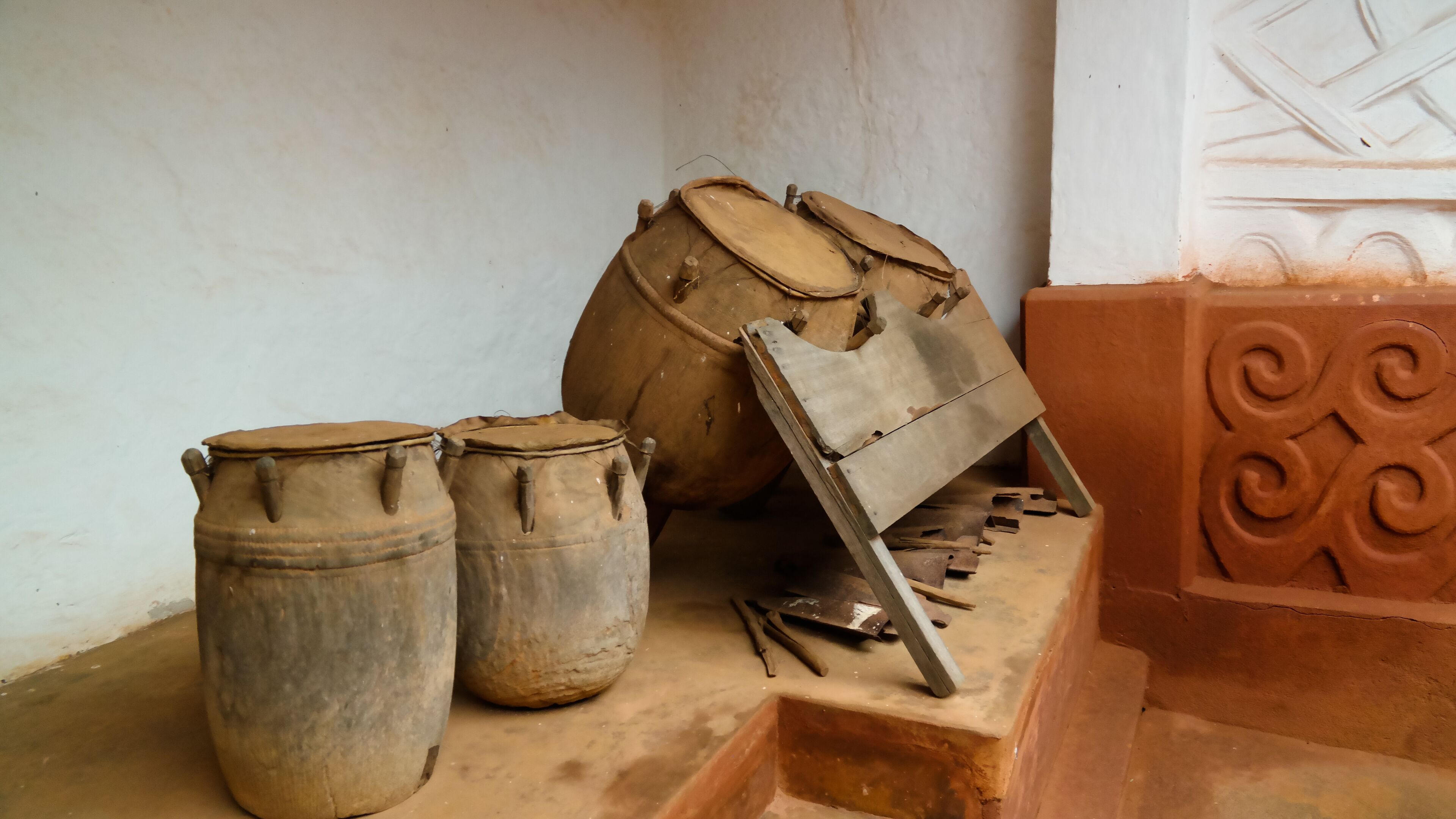 Three large clay pots and a wooden tool on a stone surface.