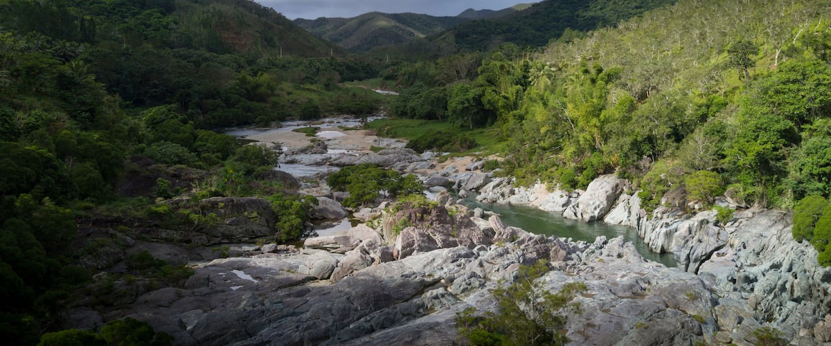 A river winding through a mountainous landscape with dense greenery and rocky terrain.