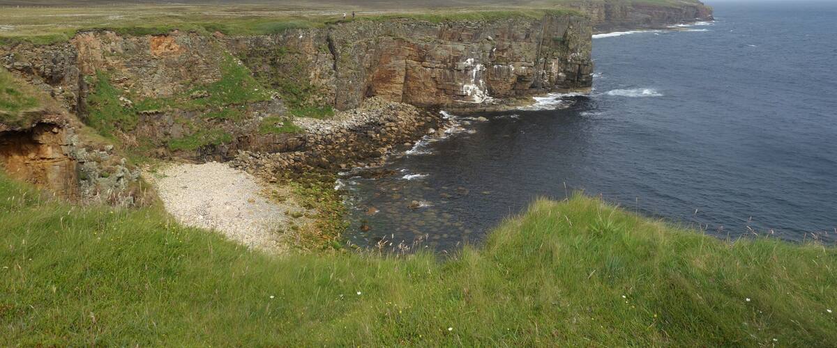 A coastal landscape with cliffs, a beach, and the ocean.