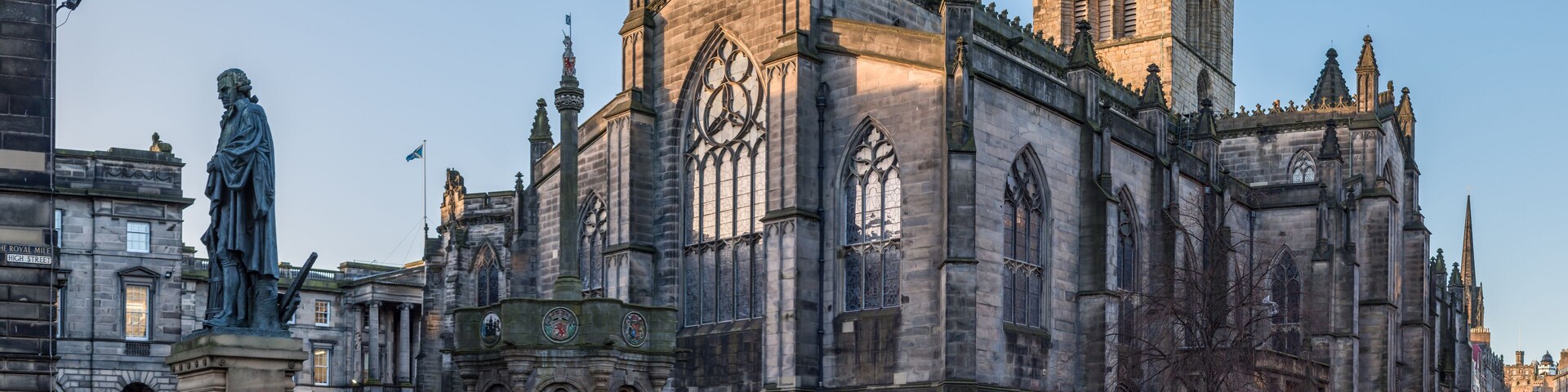 Uma catedral histórica com arquitetura gótica, uma estátua e ruas de paralelepípedos.