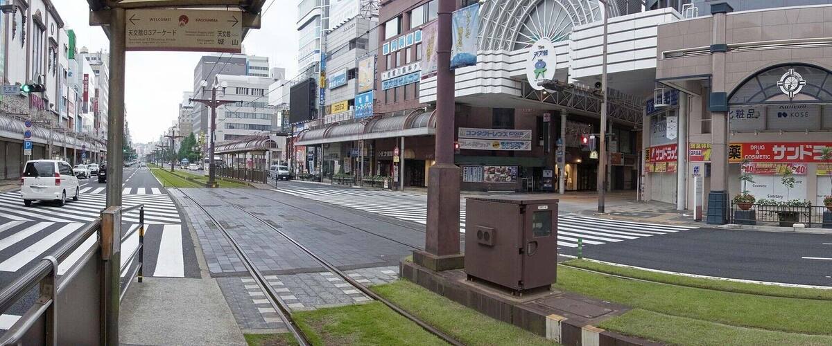 A city street with a tram, a white car, and a building with a sign that reads "COSMETIC".