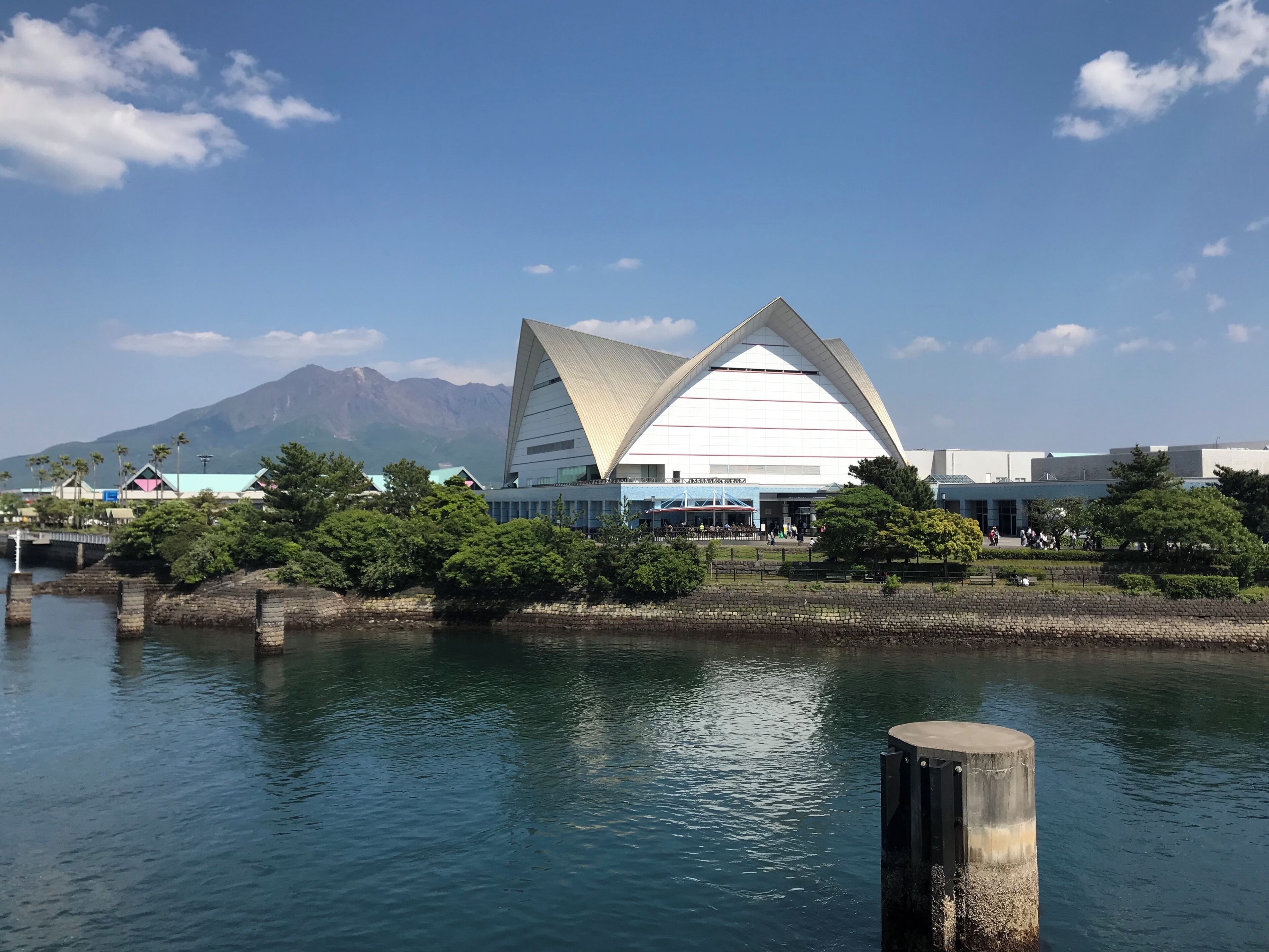 A modern building with a triangular roof near a body of water.