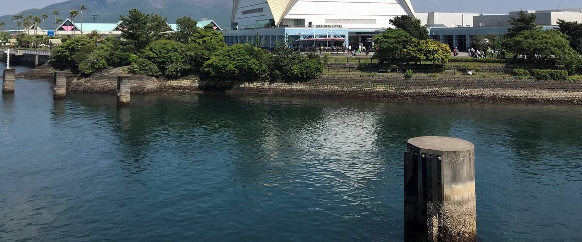 A modern building with a triangular roof near a body of water.