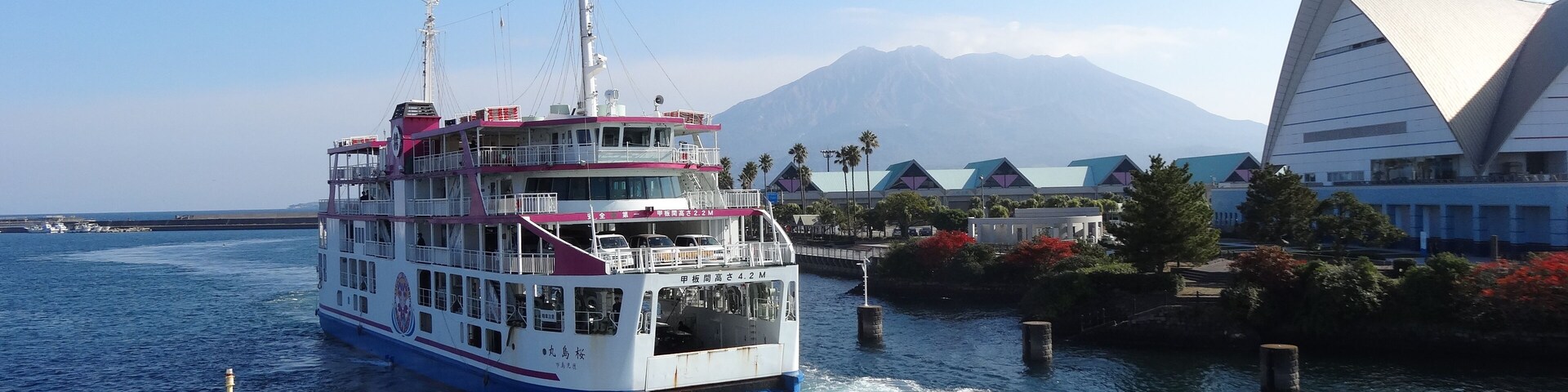 Un ferry navegando por un puerto con una montaña al fondo.