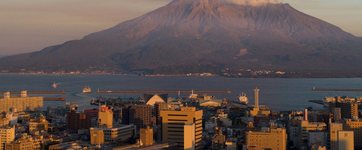A cityscape with a volcano in the background.