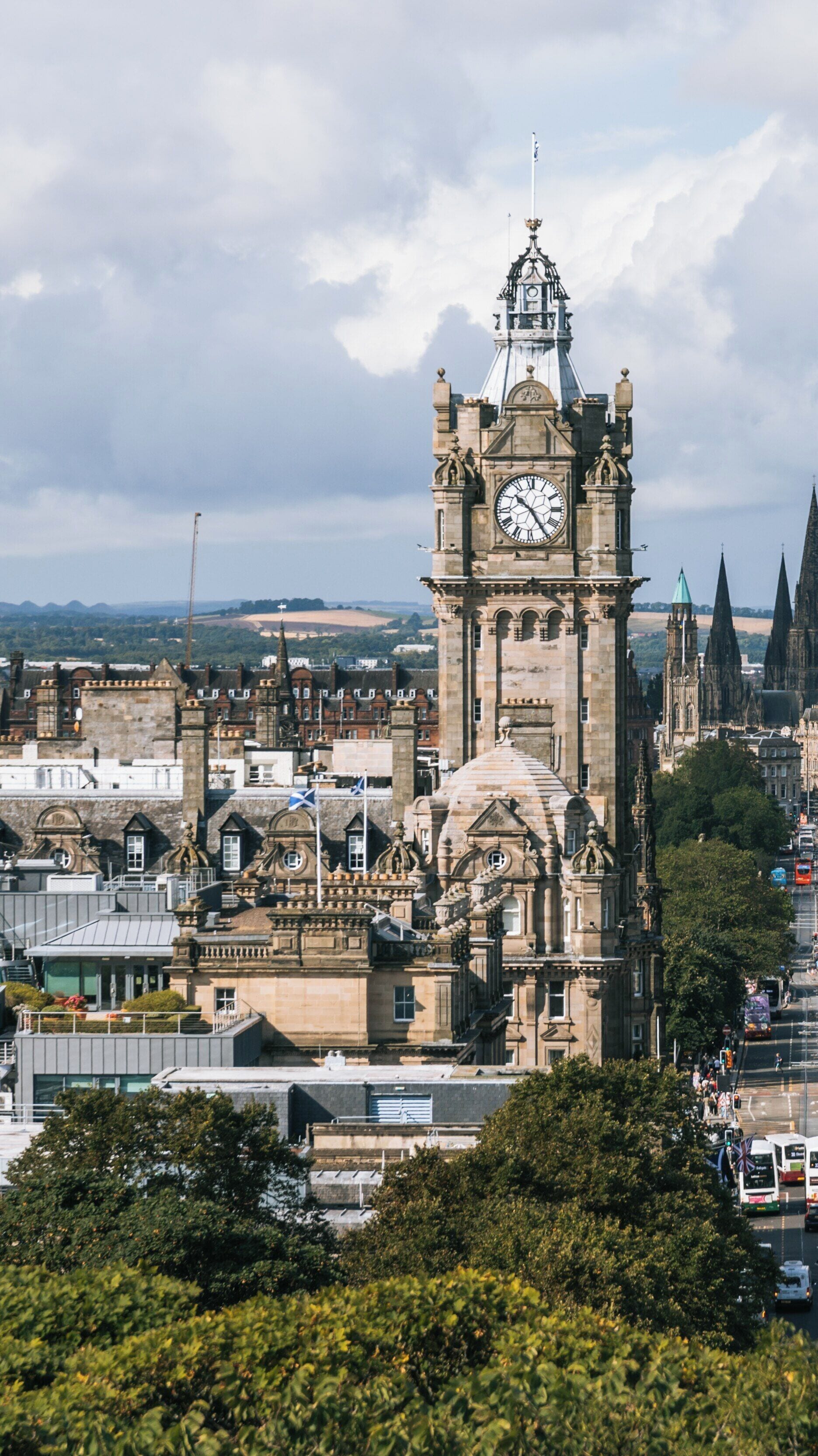 View from Calton Hill showcasing the iconic clock tower in Edinburgh's New Town with striking architecture against a cloudy sky