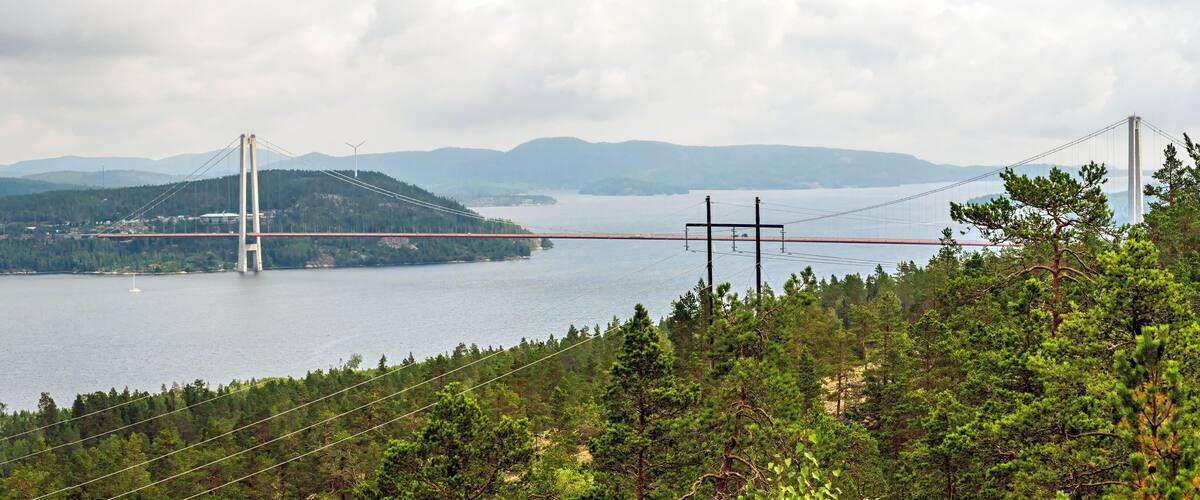 Un puente colgante sobre un lago, con montañas al fondo.