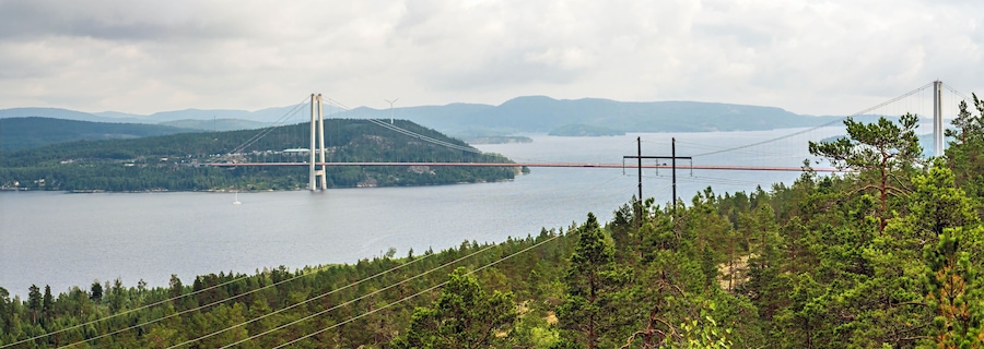 Un puente colgante sobre un lago, con montañas al fondo.