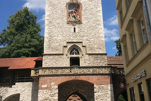 Ein historischer Turm mit einer Statue, einem Bogen und einem Gebäude mit einem Schild.