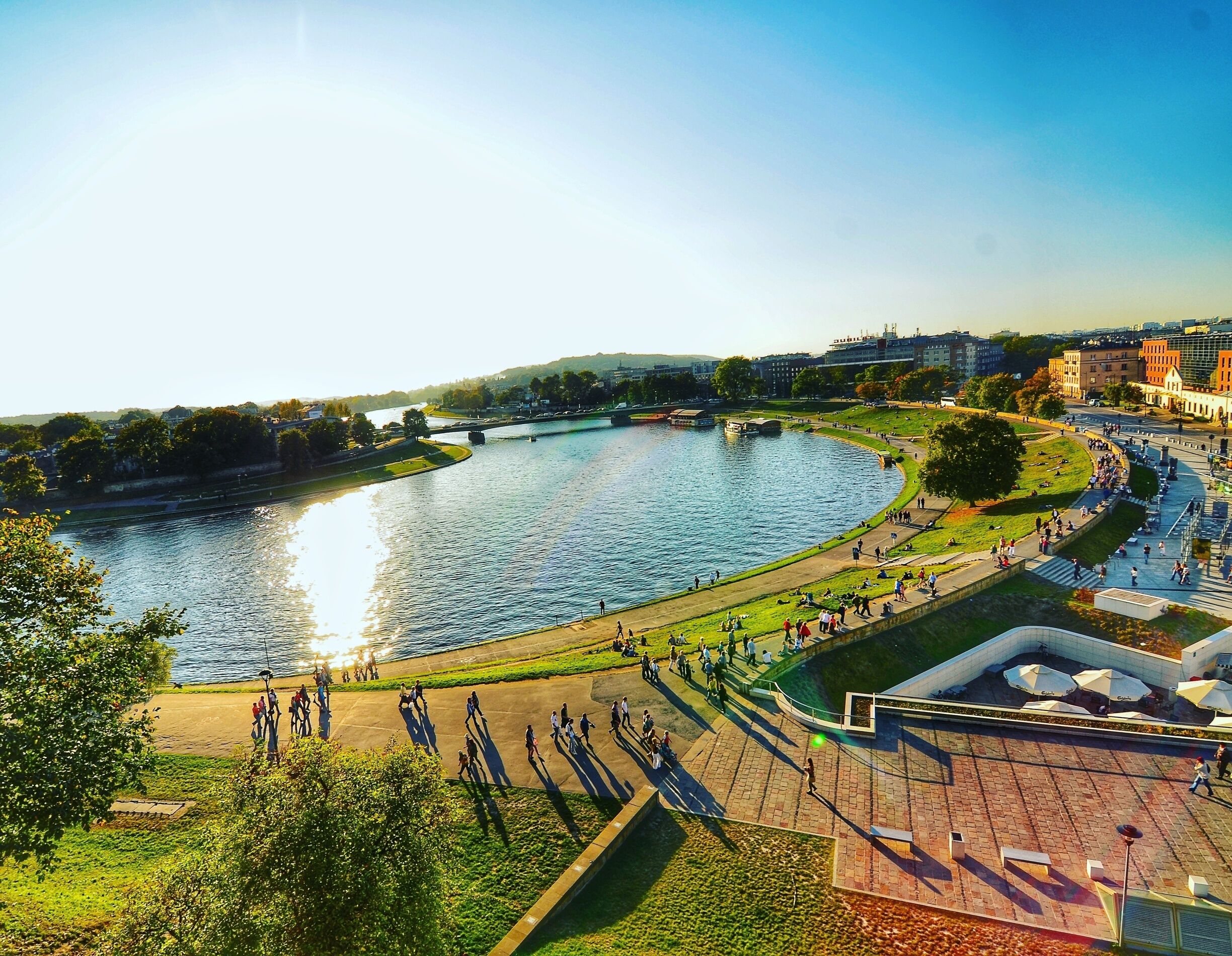 A riverside park with a curved river, walking paths, and a bridge.