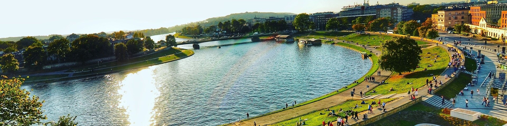 A riverside park with a curved river, walking paths, and a bridge.